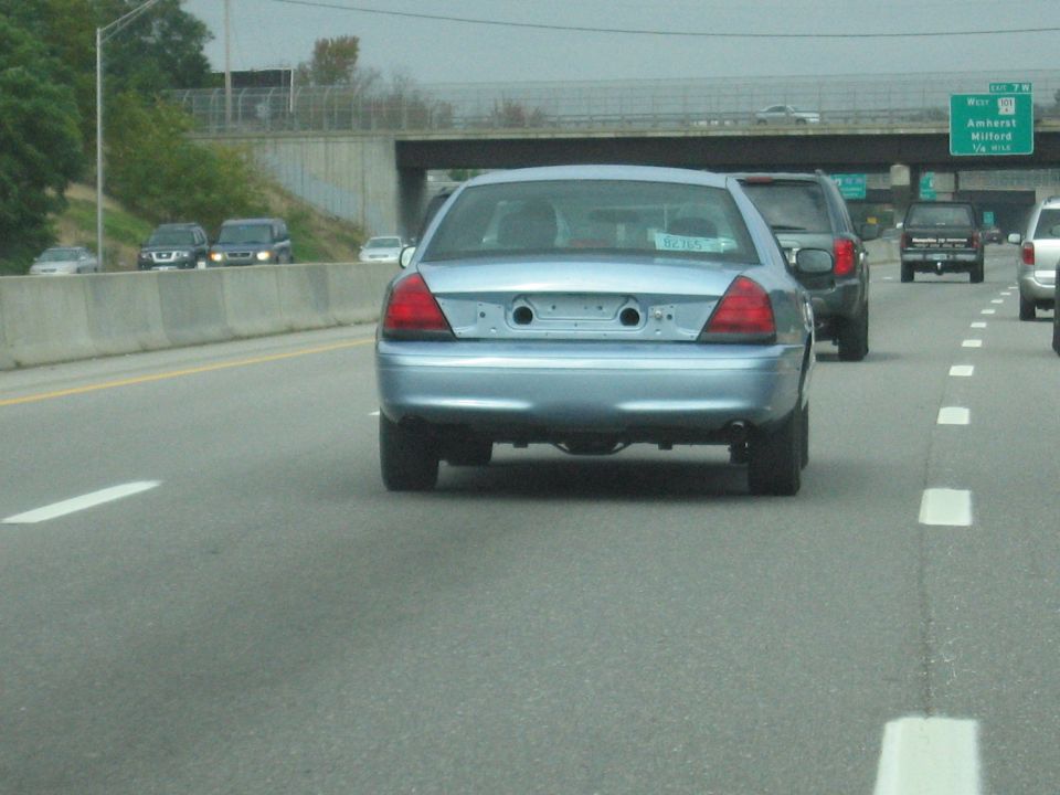 2001 Ford Crown Victoria on highway, missing license plate and bumper trim