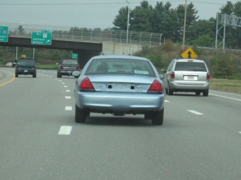2001 Ford Crown Victoria - A light blue sedan is traveling on a highway with other vehicles around it.