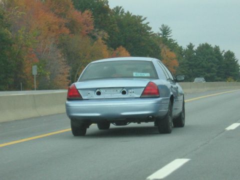 2001 Ford Crown Victoria - A light blue 2001 Ford Crown Victoria sedan is seen from behind on a highway during autumn.