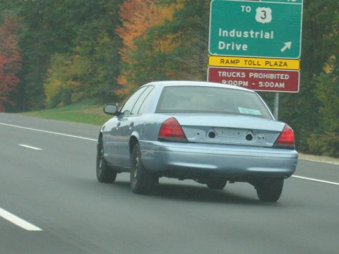 2001 Ford Crown Victoria - This 2001 Ford Crown Victoria is seen from the rear, missing its bumper and license plate, on a highway.