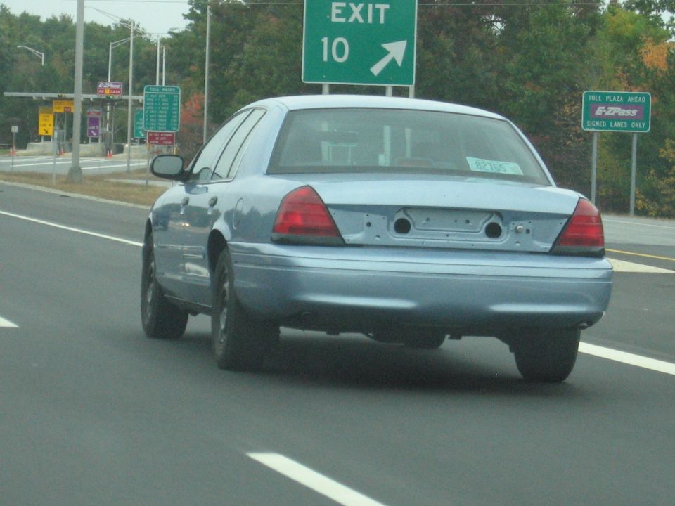 Blue 2001 Ford Crown Victoria driving on highway near toll plaza