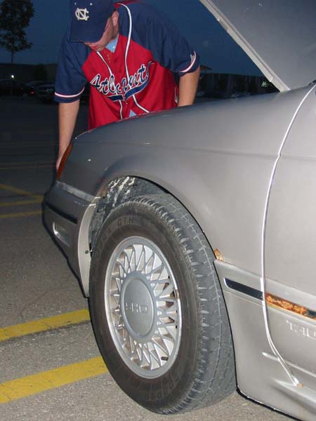 1990 Ford Taurus - Close-up of a 1990 Ford Taurus side profile, showing the front wheel and fender.