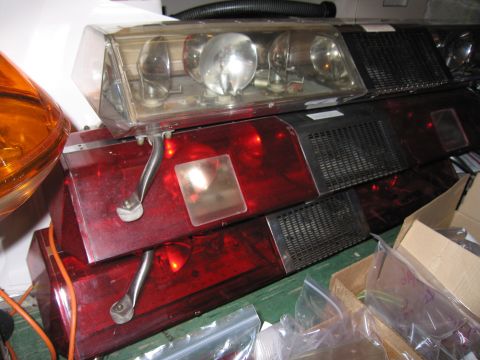 2001 Ford Crown Victoria - Several emergency light bars are stacked together, some with red lenses and others with clear lenses.