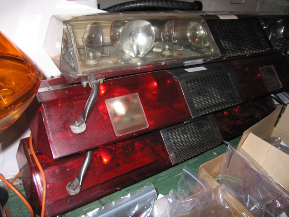 Stack of red and clear emergency light bars, some with amber lights visible