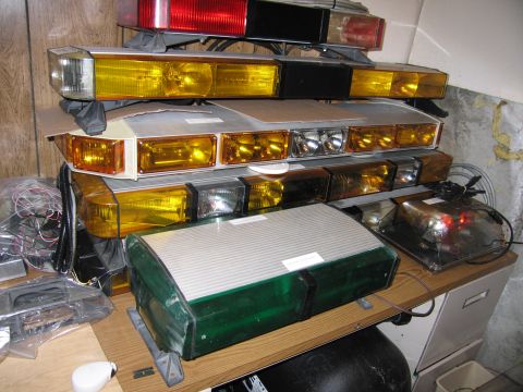 2001 Ford Crown Victoria - Various emergency light bars are stacked on a shelf, with some wiring visible.