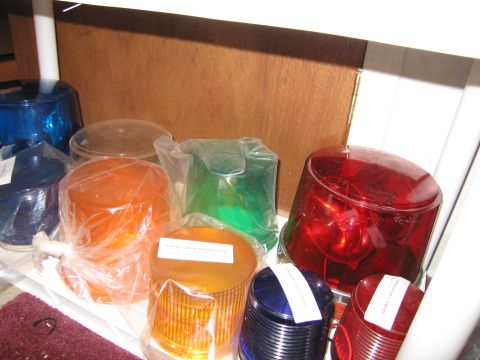 2001 Ford Crown Victoria - Several new emergency light lenses in various colors are neatly arranged on a shelf.