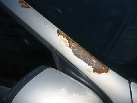 1990 Ford Taurus - Rust is visible on the A-pillar of a white car, with a side mirror in the foreground.