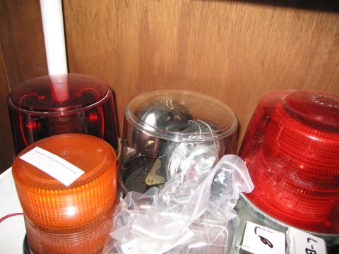 2001 Ford Crown Victoria - A collection of various emergency vehicle lights, including red and amber rotating beacons, are stored together.