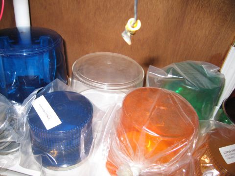 2001 Ford Crown Victoria - Several colored emergency light domes are stored in plastic packaging on a shelf.