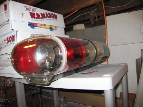 2001 Ford Crown Victoria - Emergency light bar with red and clear lenses, a visible bulb, is placed on a table with boxes in the background.