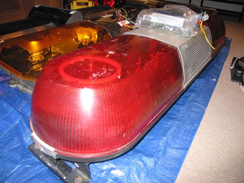 2001 Ford Crown Victoria - A red emergency light bar is shown, with wiring visible on top and an amber light bar in the background.