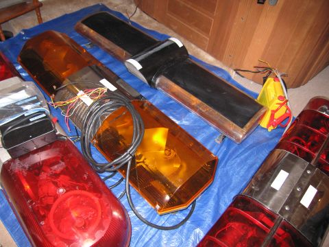 2001 Ford Crown Victoria - Several emergency light bars, including red and amber units, are laid out on a blue tarp.