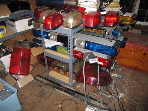 2001 Ford Crown Victoria - A collection of emergency vehicle light bars are stored on shelves and on the floor.