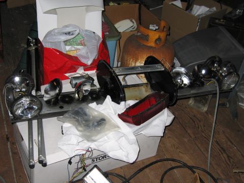 2001 Ford Crown Victoria - Various vehicle parts, including headlights and a taillight lens, are laid out on a shelf amidst clutter.