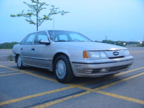 1990 Ford Taurus - Silver 1990 Ford Taurus sedan parked in a lot under a cloudy sky.