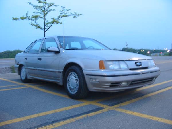 1990 Ford Taurus sedan parked in a lot, front 3/4 view