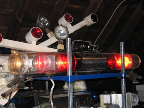 2001 Ford Crown Victoria - A collection of emergency lights and spotlights are mounted on a bracket in an attic space.