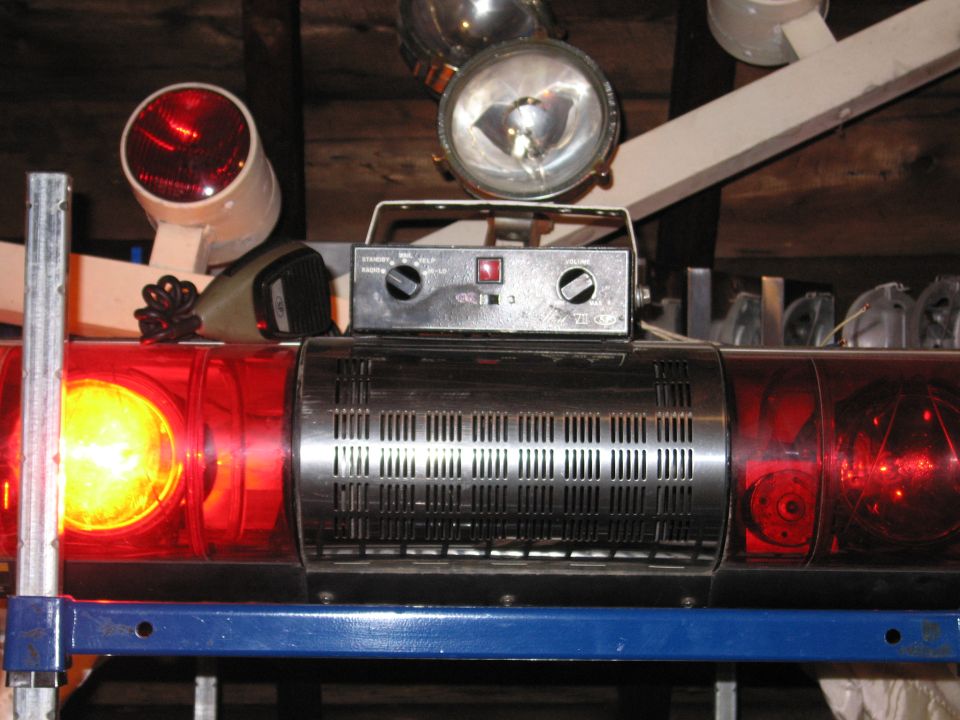 Emergency light bar with red and yellow lights, chrome grille, and control box with knobs and switches