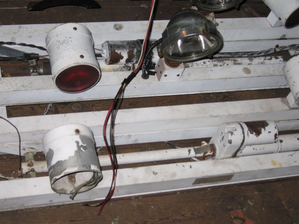 White light fixture with red and clear lamps, wires, and rusty metal components