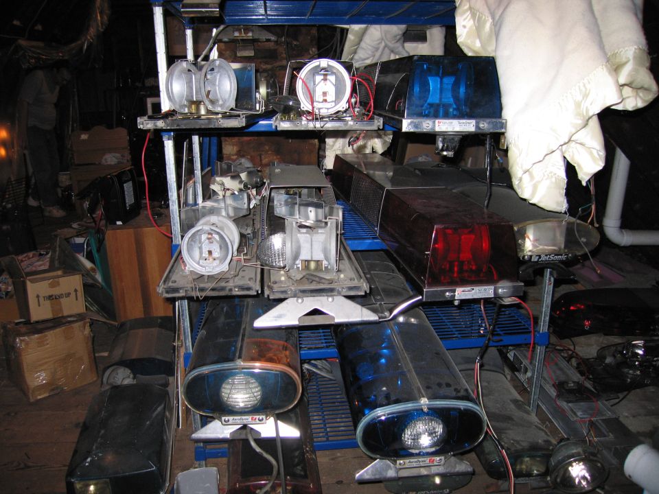 Shelves holding various police light bars, some intact, some disassembled. Includes blue and red lights