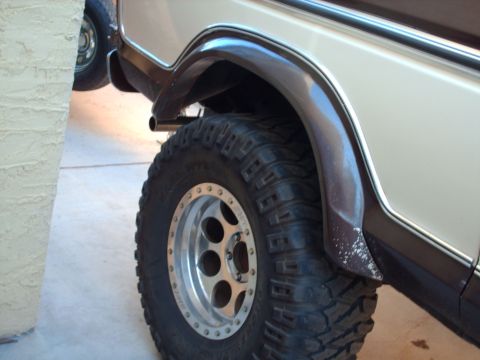 1978 Ford Bronco - Close-up of the rear wheel and fender flare of a tan and brown 1978 Ford Bronco, showing aftermarket wheels and tires.