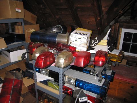 2001 Ford Crown Victoria - Various emergency light bar parts and lenses are stored on shelves in an attic space.
