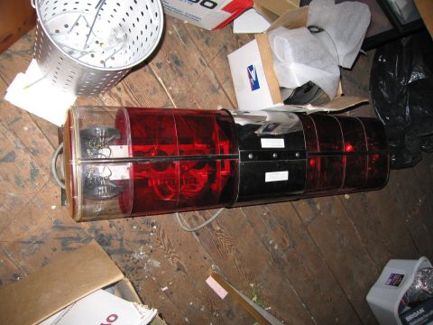 2001 Ford Crown Victoria - Emergency light bar with red and clear lenses, likely for a vehicle, on a wooden floor with debris.