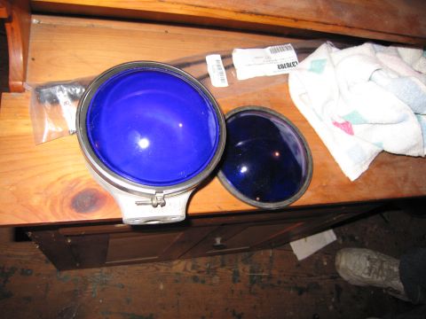 2001 Ford Crown Victoria - A blue headlight lens and its cover are displayed on a wooden table next to a towel and packaging.