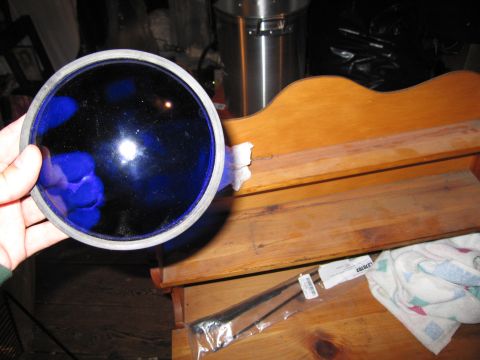 2001 Ford Crown Victoria - Hand holds a blue glass part. Package of windshield wipers visible on wooden shelf.