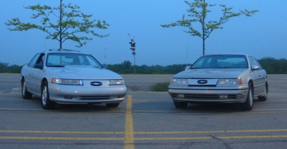 two silver Ford Taurus sedans parked side-by-side at dusk