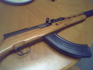 1990 Ford Bronco - An SKS rifle with a high-capacity banana magazine is shown on a wooden surface, with a Supermotors.net watermark.