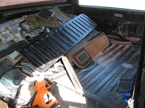 1990 Ford Bronco - Various disassembled interior parts are stored in the bed of a vehicle, obscuring the original vehicle's details.