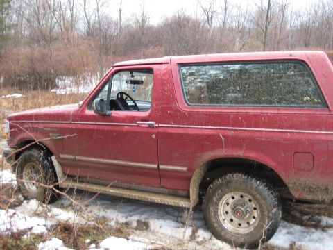 1994 Ford Bronco - Side view of a red 1994 Ford Bronco in a snowy, wooded environment.