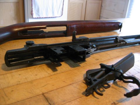 1996 Ford Bronco - Firearm parts laid out on a wooden table, showing disassembled receiver and stock.