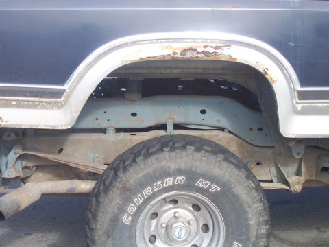 1996 Ford Bronco - The rear wheel well of a 1996 Ford Bronco shows significant rust around the fender flare and on the frame, with a Courser MT tire visible.