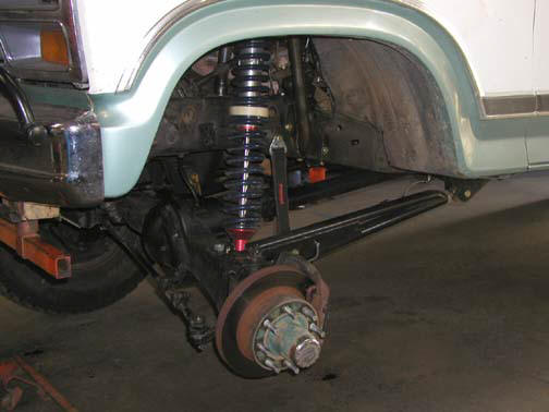 Coilover shock and radius arm at the bare front hub of a green and white Ford truck