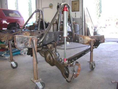 1984 Ford Bronco - The chassis of a vehicle is elevated on stands in a garage, undergoing modifications.