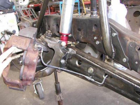 1984 Ford Bronco - Close-up view of a vehicle's front suspension and brake components, a shock absorber with red accents.