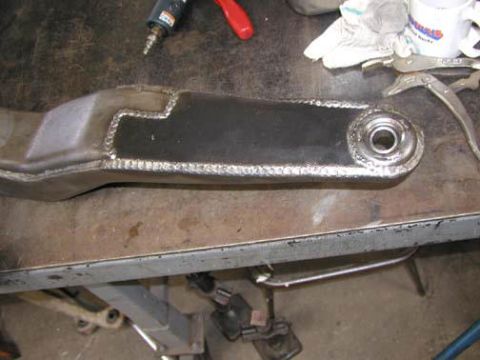 1984 Ford Bronco - A metal suspension part with visible welds and a bearing race is on a workbench.