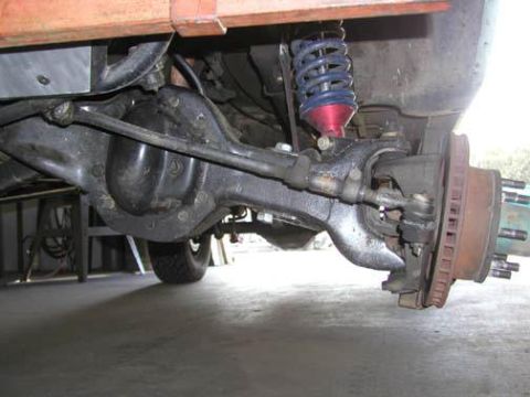 1984 Ford Bronco - Close-up view of the underside of a vehicle's front axle and suspension system.