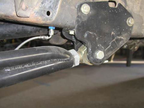 1984 Ford Bronco - A close-up view of a vehicle's suspension system, highlighting a braided hose and a blue fitting.