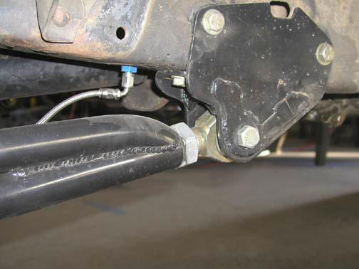 Close-up of a suspension component with a blue fitting and braided hose