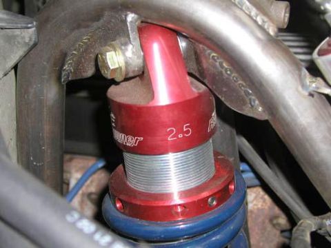 1984 Ford Bronco - Close-up of a red coilover shock absorber with a "2.5" marking, part of a vehicle's suspension system.