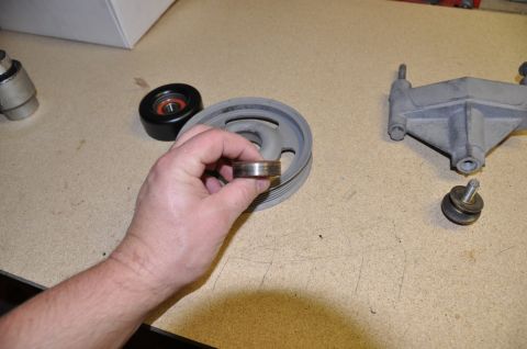 1996 Ford Bronco - A hand holds a worn bearing, with a pulley and bracket nearby, suggesting a repair or maintenance context.