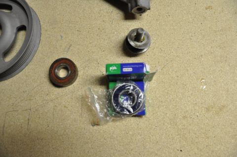 1996 Ford Bronco - Pulley and new bearings are laid out on a workbench surface.