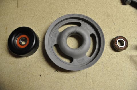 1996 Ford Bronco - Three automotive pulleys and bearings are laid out on a textured surface.