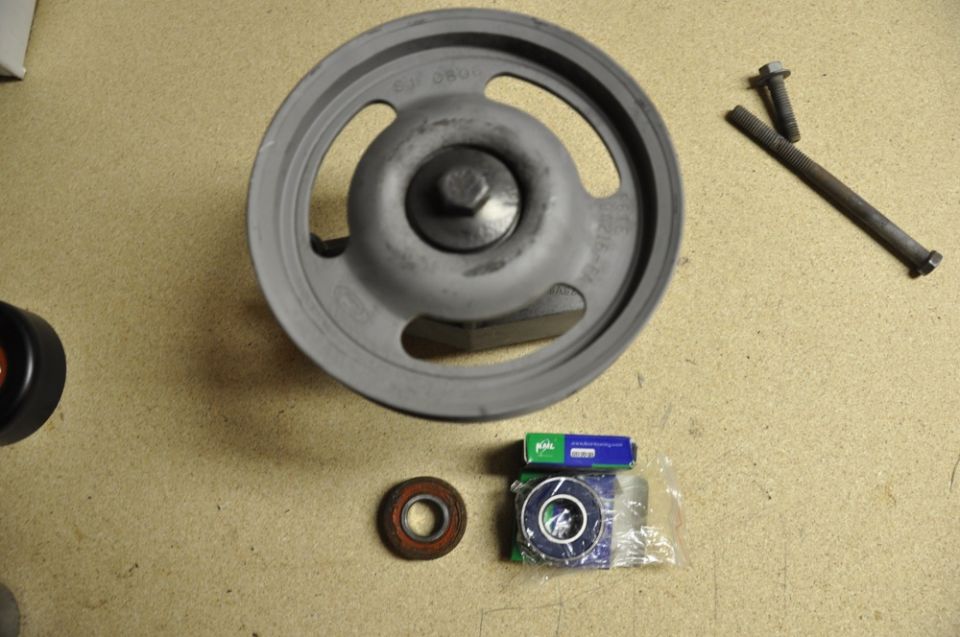 Pulley, two bearings, and two bolts on a tan surface