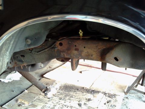 1996 Ford Bronco - Close-up view of the undercarriage of a vehicle, showing significant rust on the frame and suspension parts.