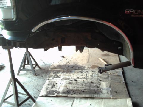 1996 Ford Bronco - The frame and undercarriage of a 1996 Ford Bronco are visible as it is supported by jack stands.