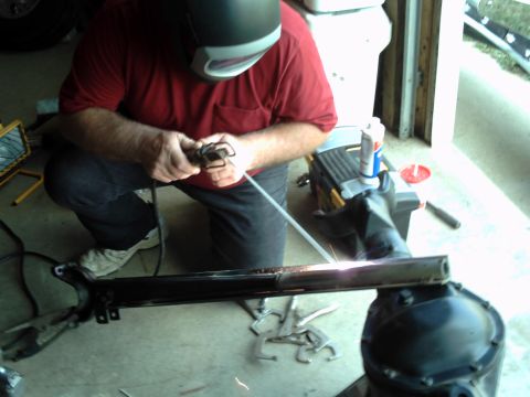 1996 Ford Bronco - A person welds a vehicle frame component in a garage setting.